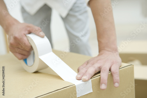 hand of man taping on cardboard box