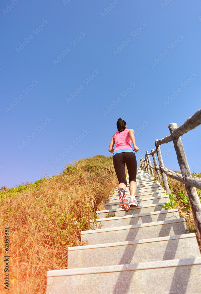 fitness woman running up on mountain stairs to peak