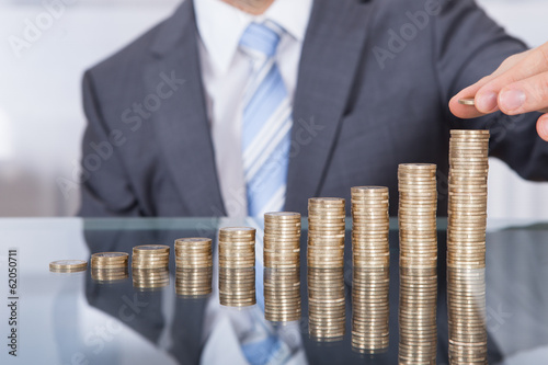 Businessperson With Stack Of Coins
