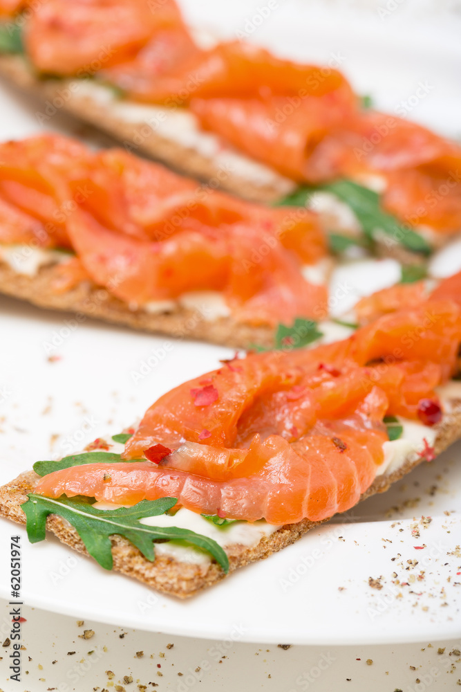 Salted salmon on crispy bread with cheese and arugula Salted salmon on crispy bread with cheese and arugula