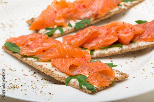 Salted salmon on crispy bread with cheese and arugula