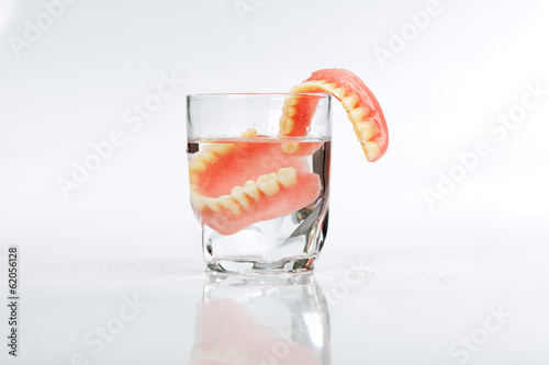 Fototapeta Naklejka Na Ścianę i Meble -  A set of dentures in a glass of water on a white background
