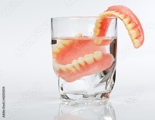 A set of dentures in a glass of water on a white background