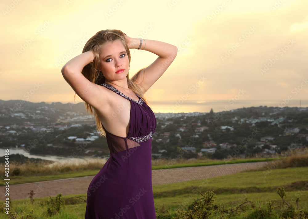 Obraz premium Attractive blonde lady on hill over town