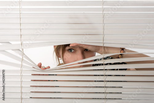 The woman looks through jalousie