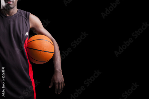 Image of a basketball player holding a ball against dark backgro © cristovao31
