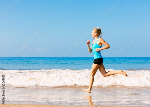 Sporty blonde woman in sportswear jogging on a sunny beach © EpicStockMedia