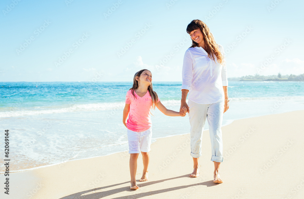 Happy mother and young daughter walking on the beach