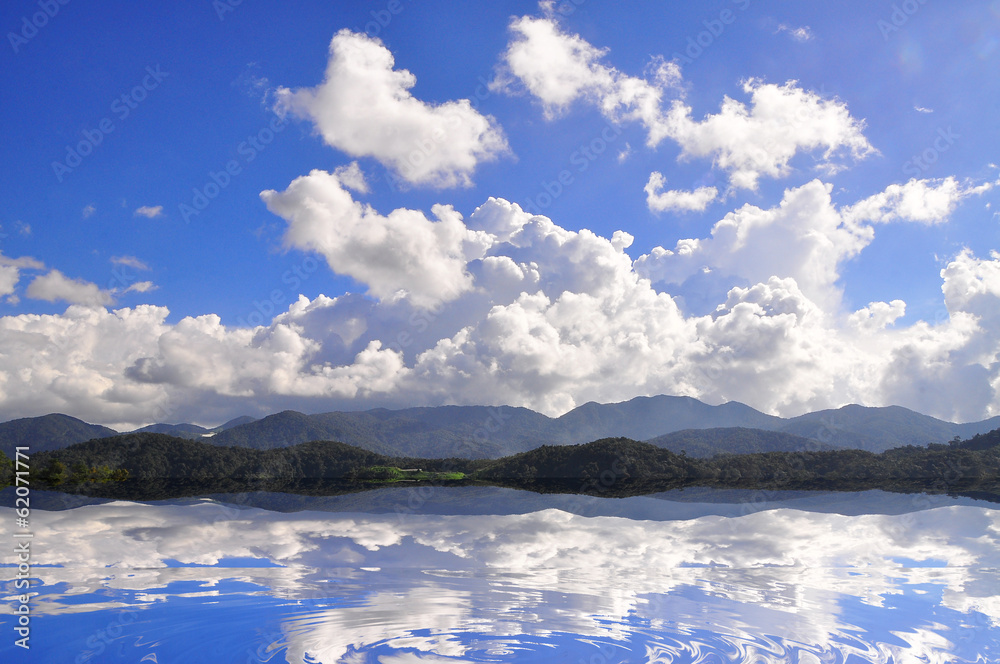 Reflection Of Clouds, Mountains And Blue Sky Over The Lake