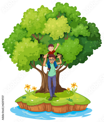 A young boy carried by his father near the big tree