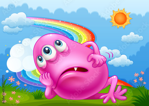 A tired pink monster at the hilltop with a rainbow in the sky