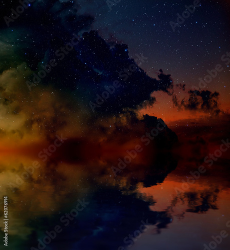 Nebula and stars reflected in water surface.