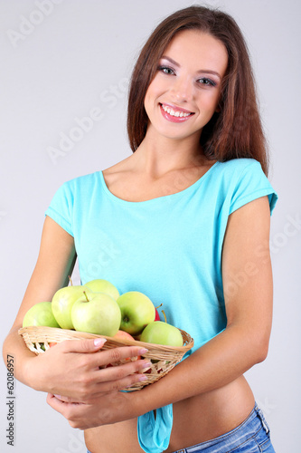 Beautiful young woman with basket of green apples