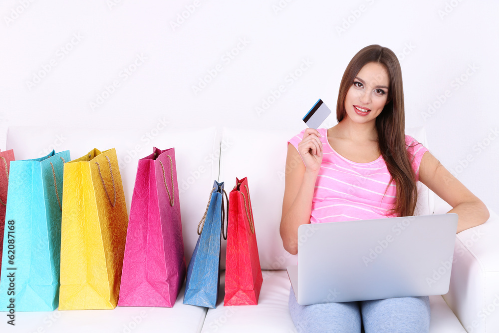 Beautiful young woman holding laptop with shopping bags Beautiful young woman holding laptop with shopping bags