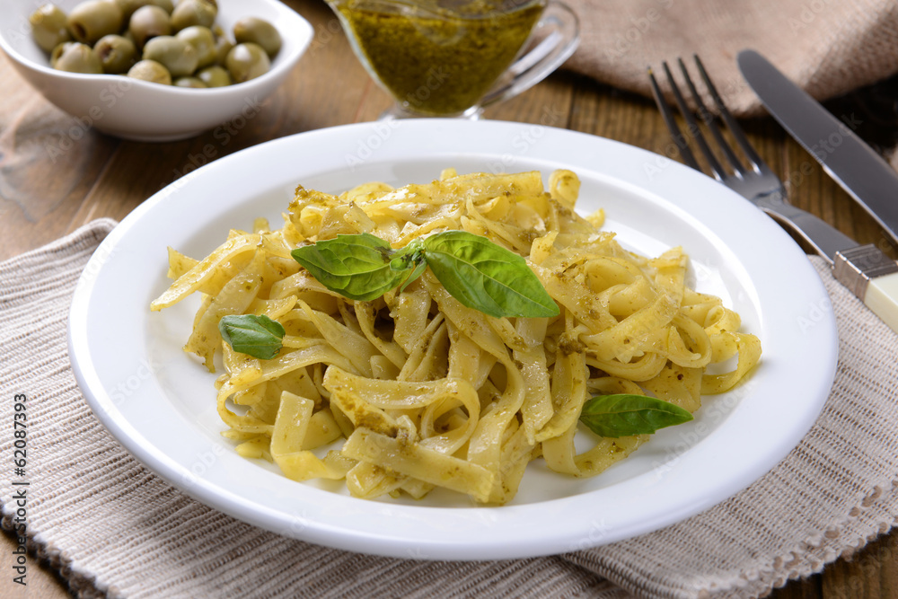 Delicious pasta with pesto on plate on table close-up