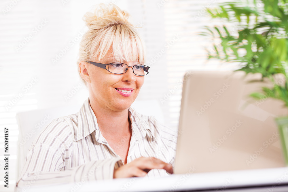 Business woman working at laptop in the office. Business woman working at laptop in the office.