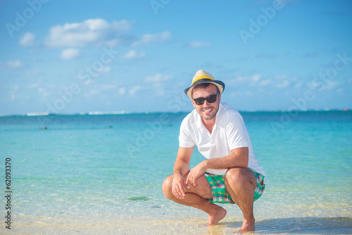 casual man  standing crouched on a tropical beach