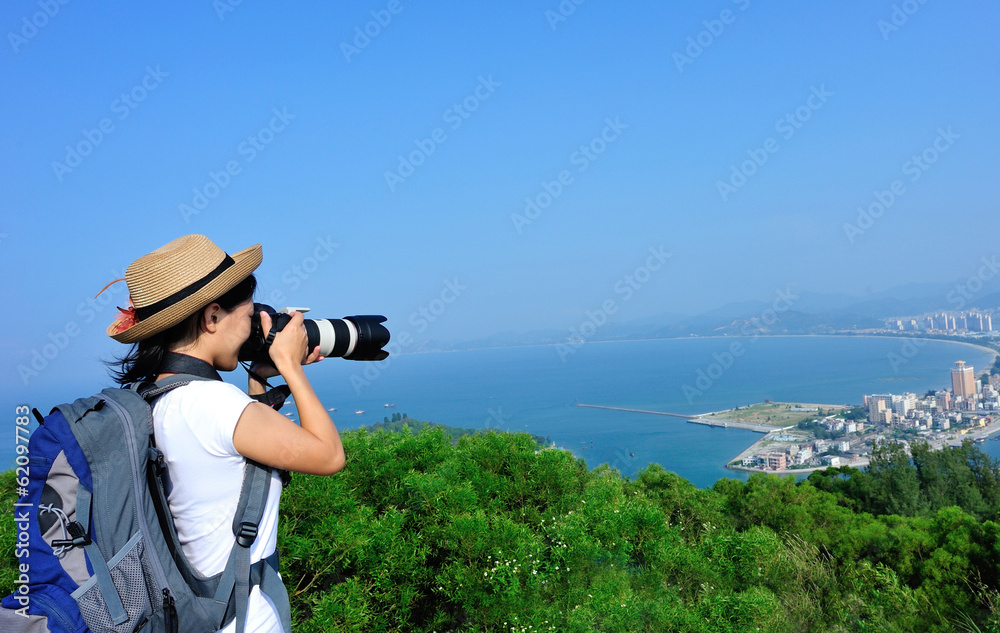  woman photographer taking photo on seaside mountain peak