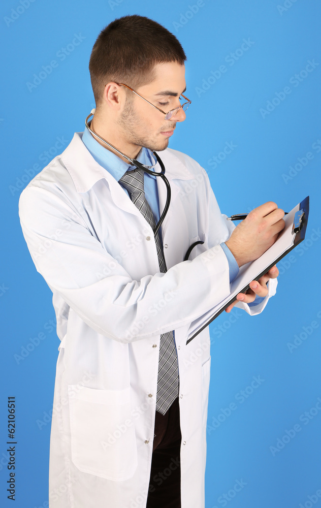 Male Doctor standing with folder, on blue background Male Doctor standing with folder, on blue background
