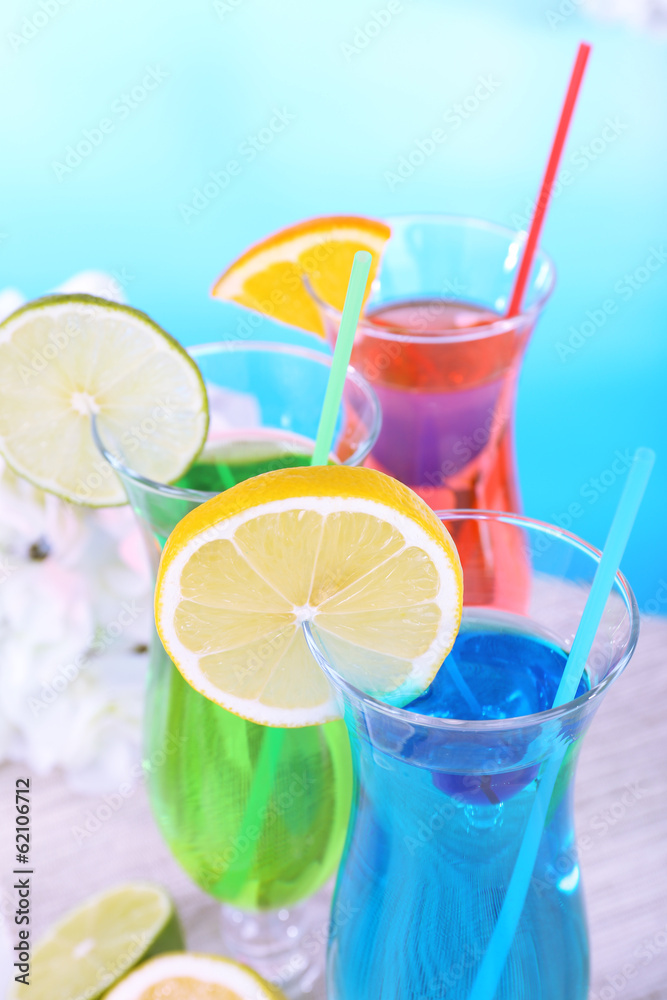 Fototapeta premium Glasses of cocktails on table on light blue background