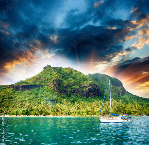 Obraz na płótnie Polynesia. Island and vegetation at sunset with small boat on fo