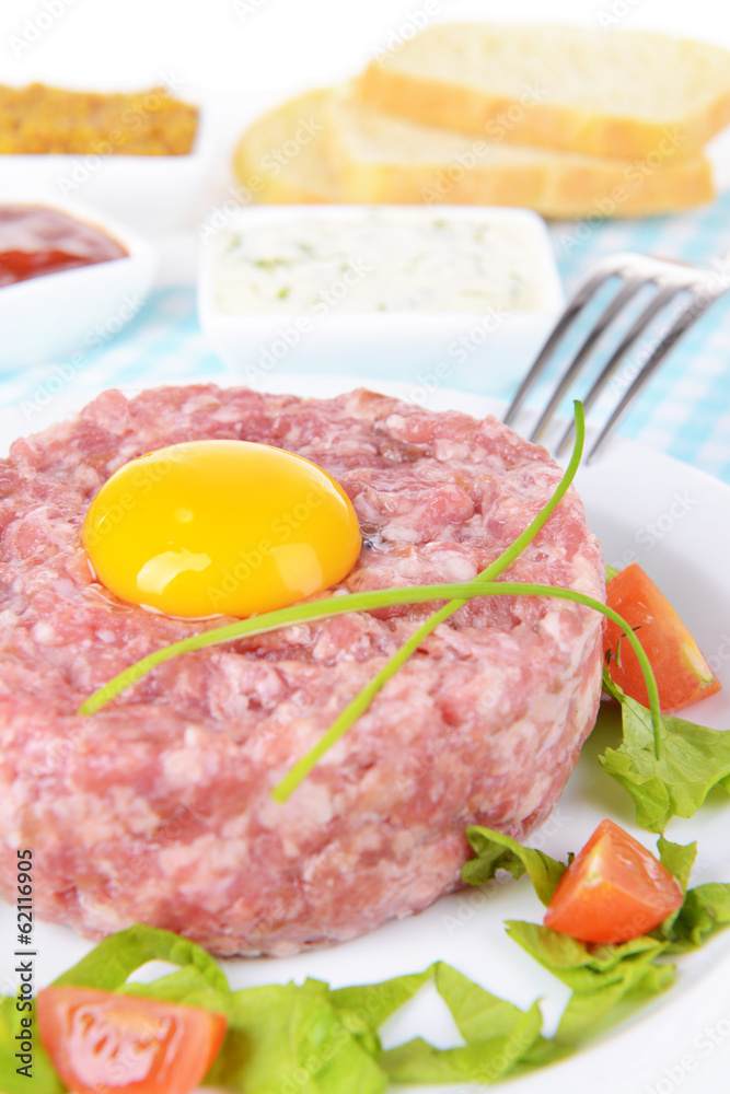 Delicious steak tartare with yolk on plate on table close-up Delicious steak tartare with yolk on plate on table close-up