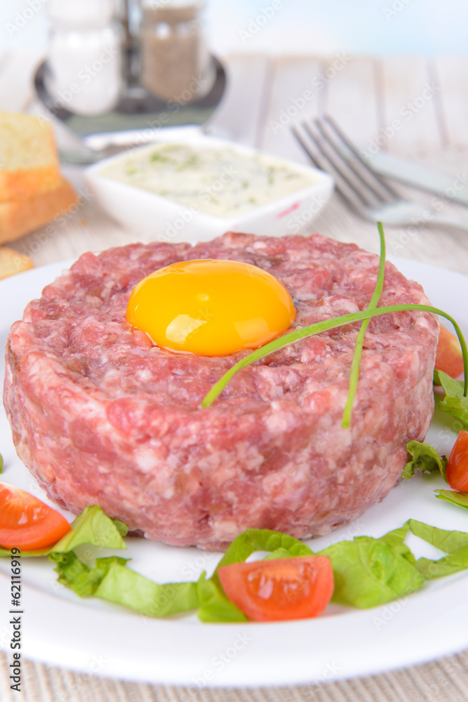 Delicious steak tartare with yolk on plate on table close-up