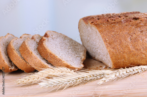 Sliced bread on wooden board on bright background