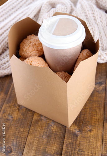 Hot coffee and cookies in box on wooden table close-up