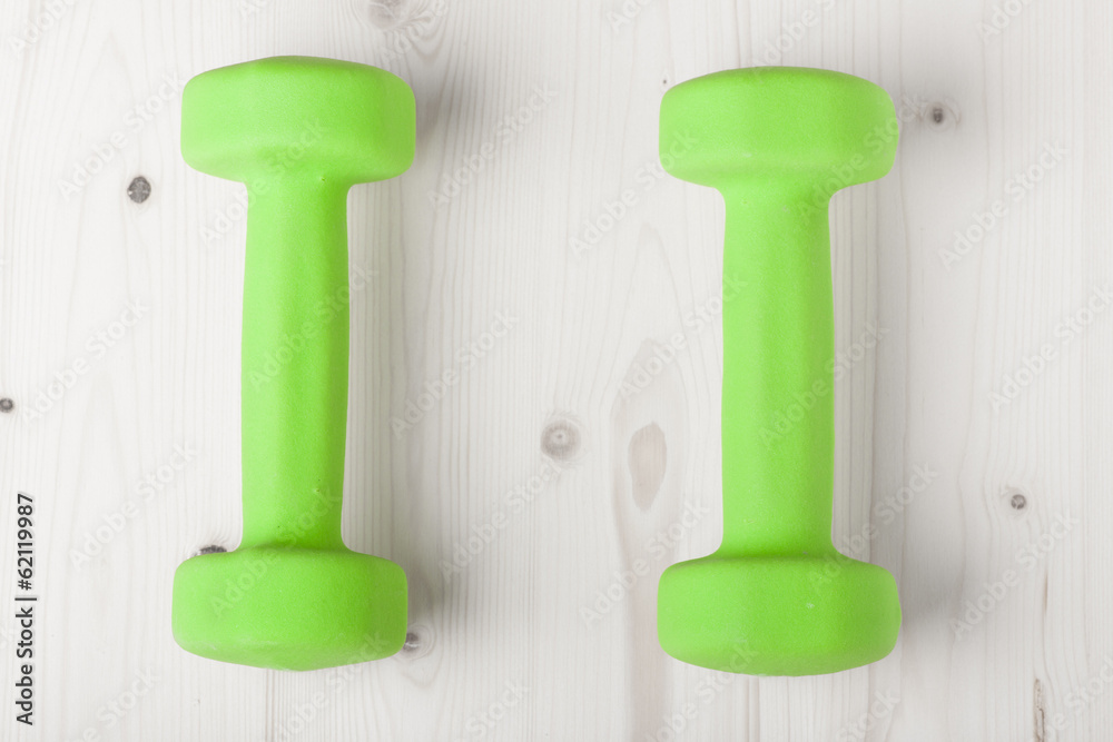 small green dumbbells on wooden surface small green dumbbells on wooden surface