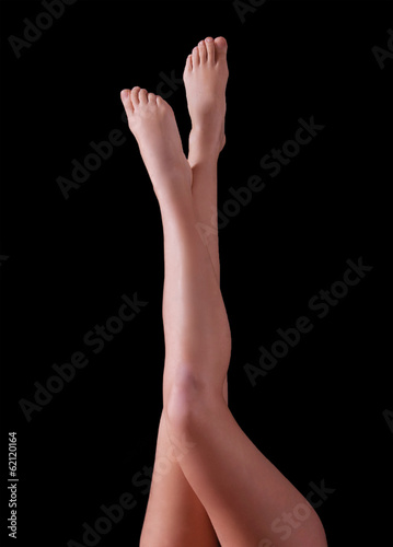 Slender female legs, isolated on black background