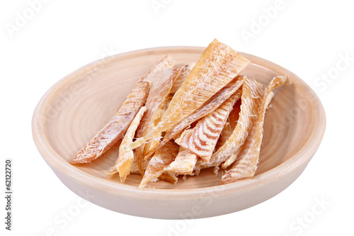 Slices of dried fish on wooden plate isolated over white. photo