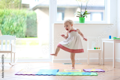 Happy blonde toddler girl having fun dancing indoors