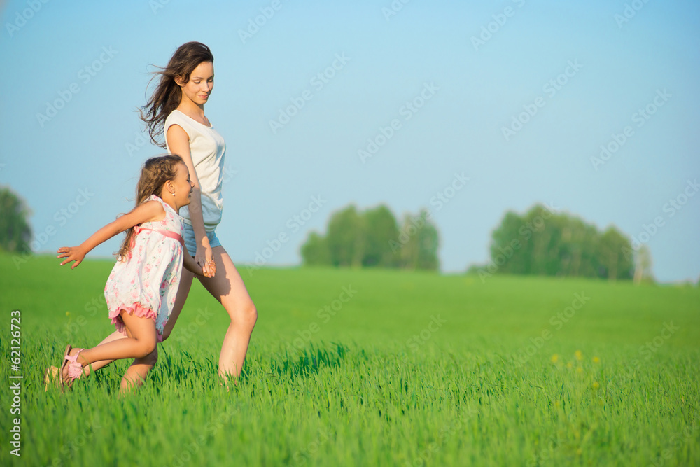 Young happy girls running at green wheat field
