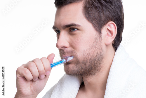 Happy young man brushing teeth.