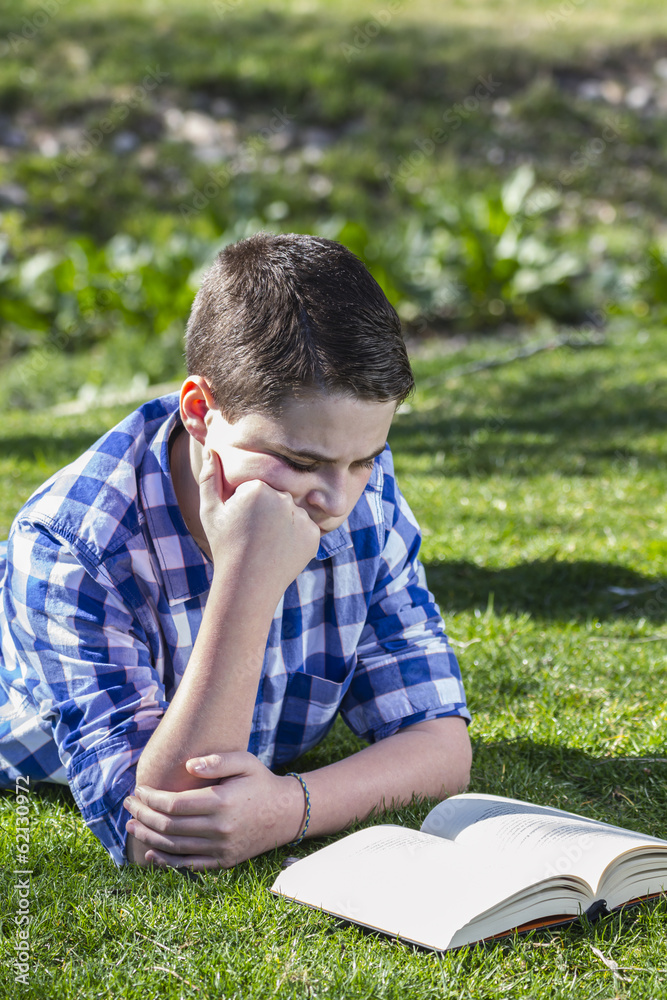 Young boy reading a book in the woods with shallow depth of fiel Young boy reading a book in the woods with shallow depth of fiel