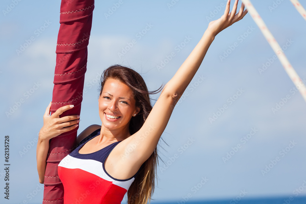 Happy woman on the bow of a Sail Boat with arm raised. Copy space