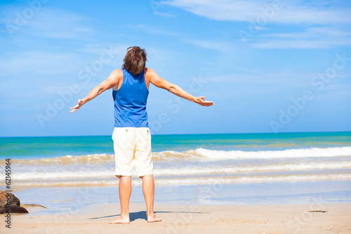 man waving hands at the beach, enjoying his time tanning