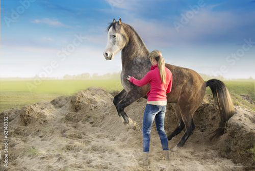 Woman and rising arabian horse on background of sand and fields photo