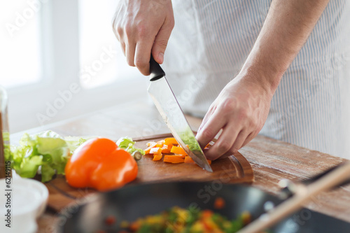 close up of male hand cutting pepper on board