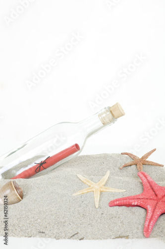 Glass bottle with note inside on sand, on white background