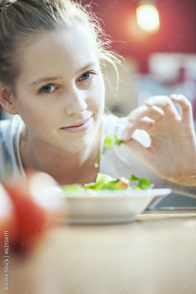 Young woman in her kitchen holding an aromatic herb for her sala Young woman in her kitchen holding an aromatic herb for her sala