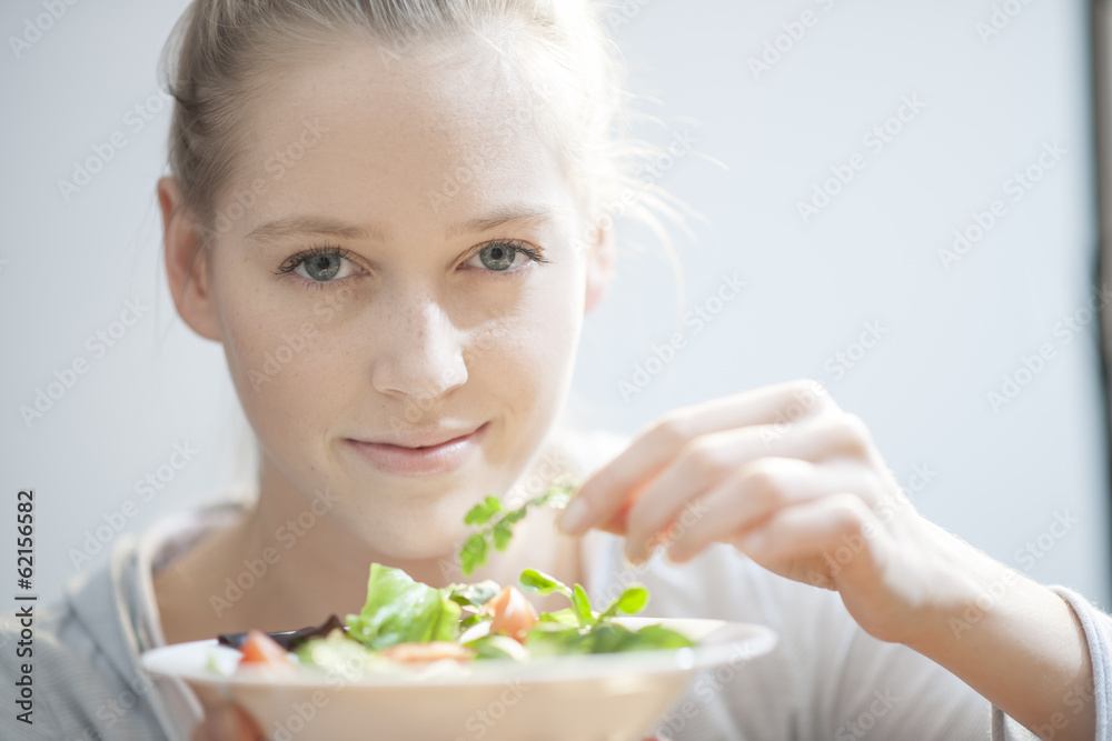 Young woman in her kitchen holding an aromatic herb for her sala Young woman in her kitchen holding an aromatic herb for her sala