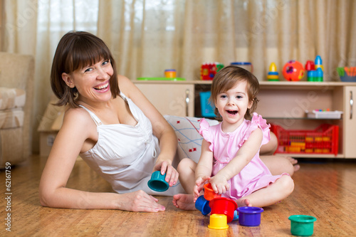 kid girl and mom playing together with cup toys