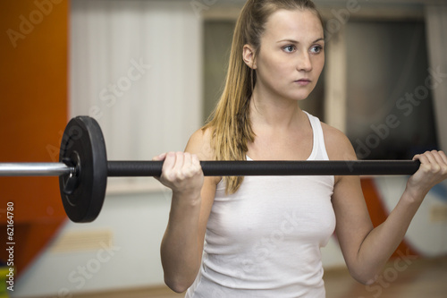 Young athlete woman exercising with barbell