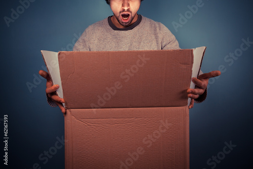 Surprised young man opening exciting box