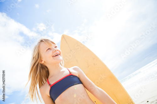 Happy young girl with surfboard at beach