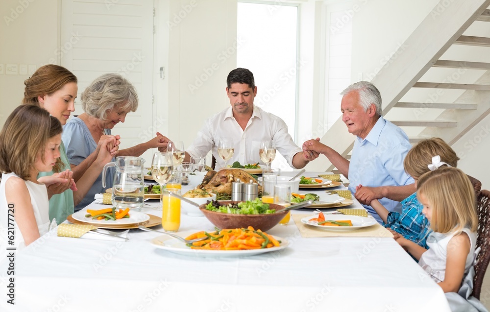 Family praying together before meal at dining table Family praying together before meal at dining table