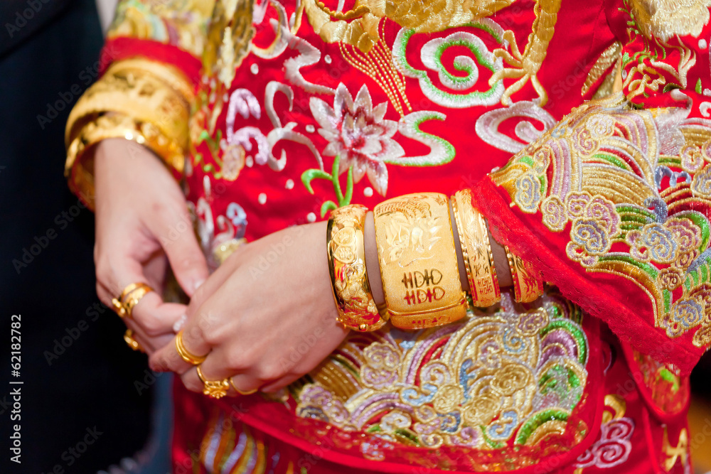 Numerous golden wedding bangles on Chinese bride