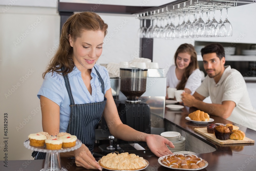 Cafe owner holding sweet snacks with couple at counter in Cafe owner holding sweet snacks with couple at counter in